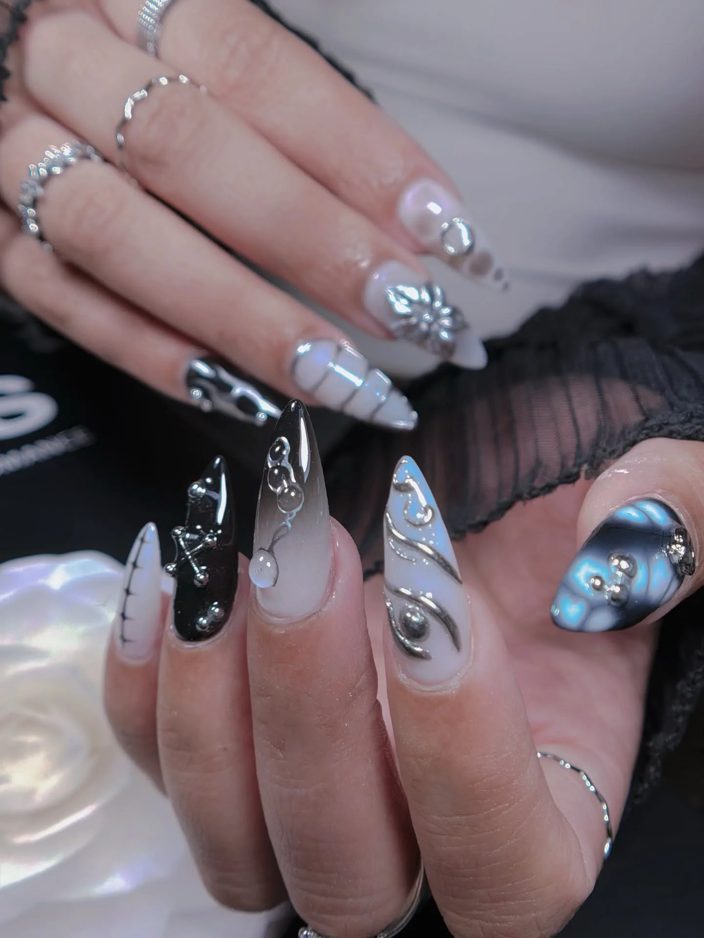 Silver-chrome and clear 3D sculpted gothic nail art on dark backdrop