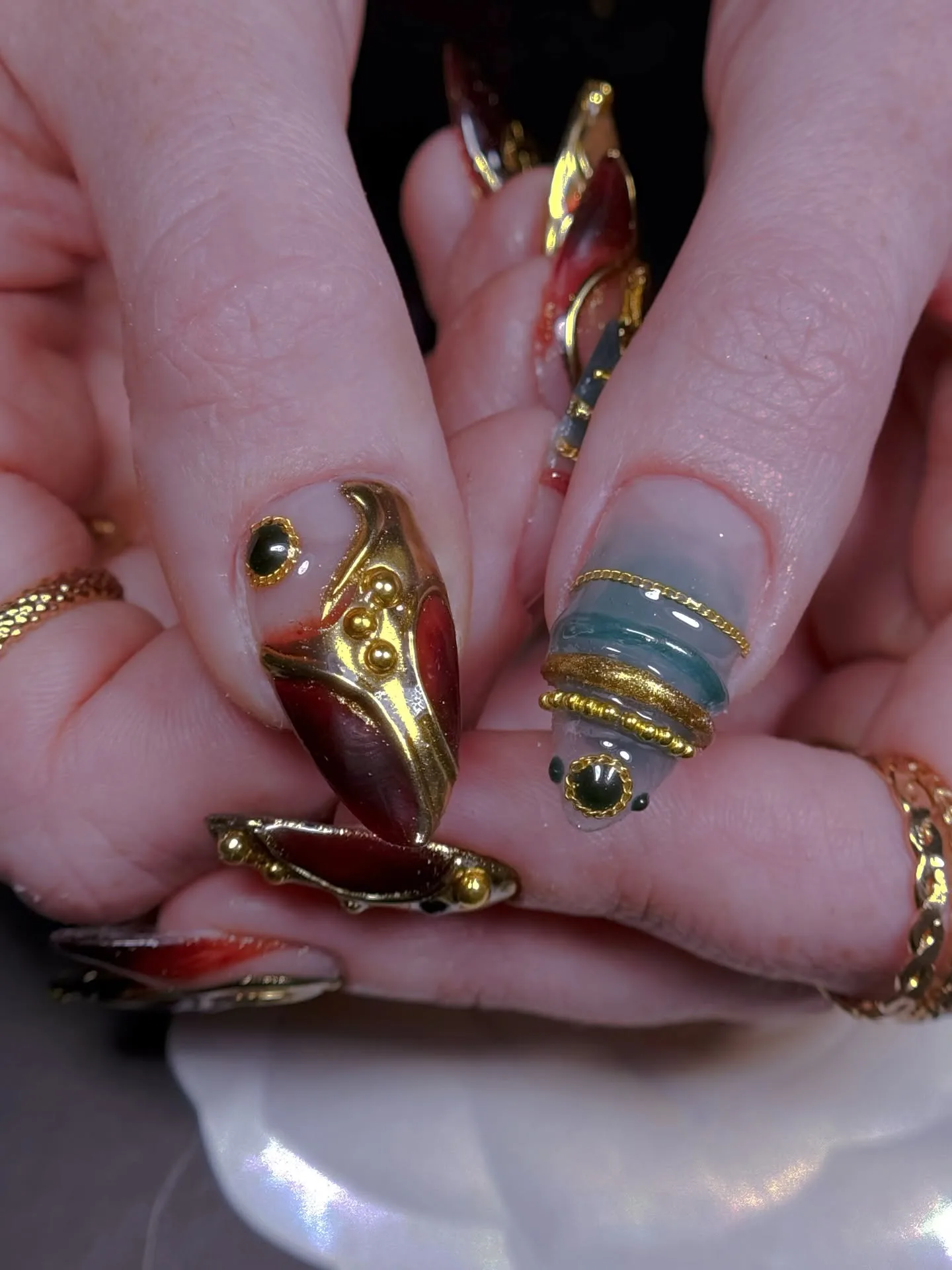 Red, gold and jade gemstone ornate nails, tight close-up
